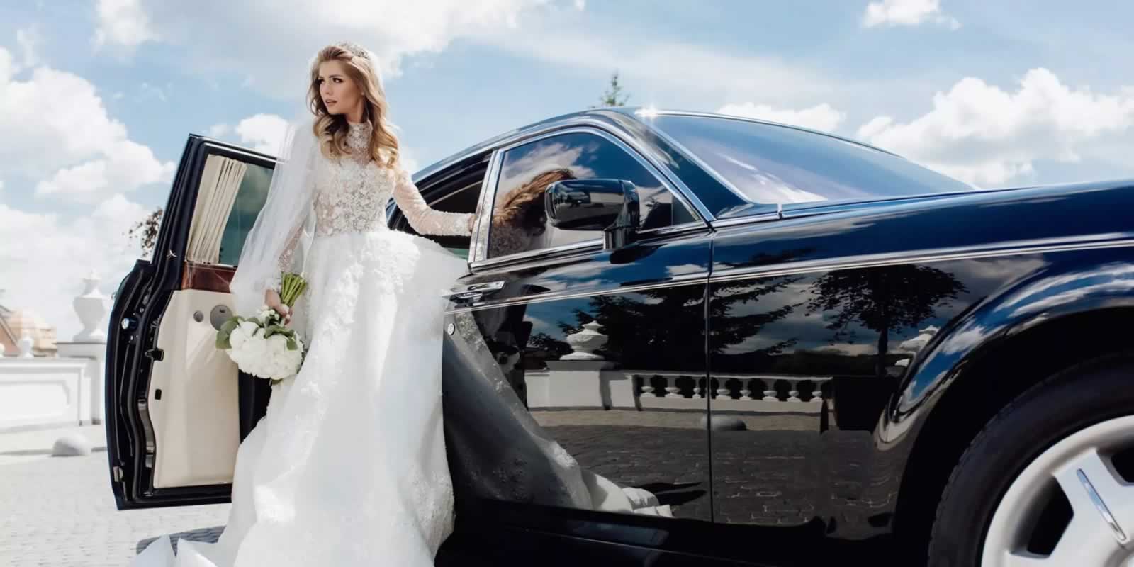 Bride standing beside a black Rolls Royce wedding car