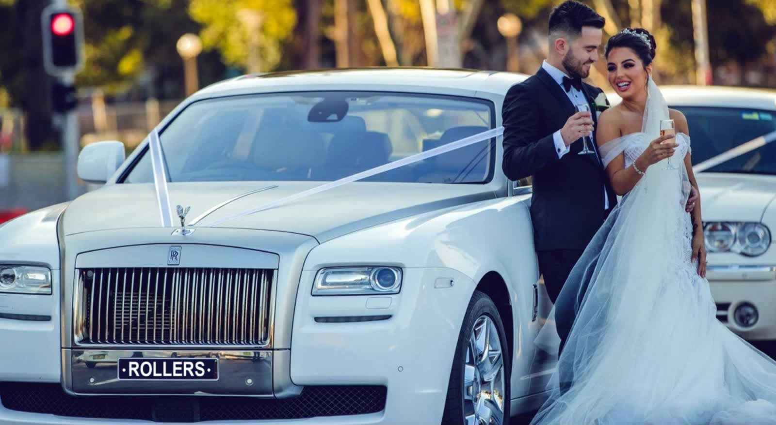 Happy coupole drink champagne beside a Rolls-Royce wedding car