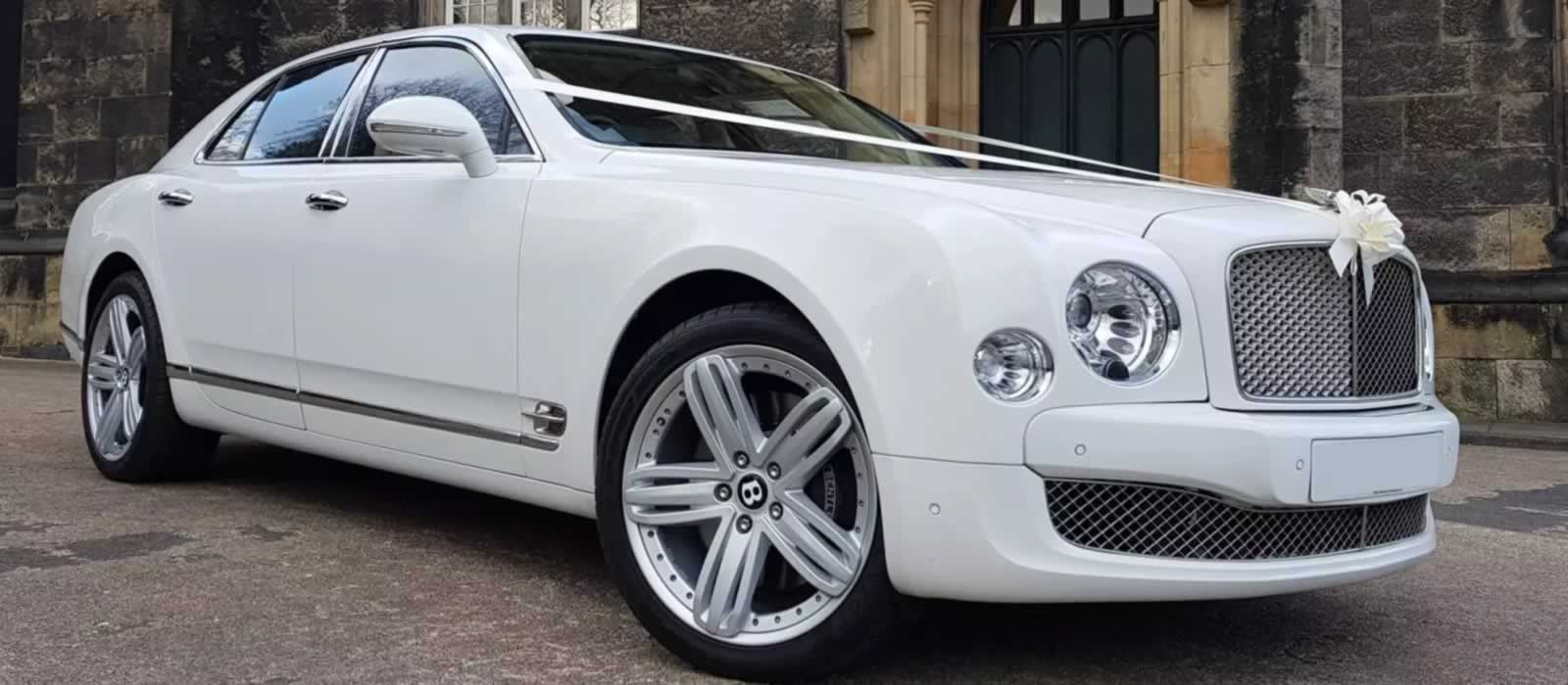 White Bentley Mulsanne with wedding ribbons on bonnet