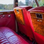 Interior red leather seating and drop down picnic tables in a Rolls-Royce Silver Cloud limousine