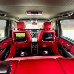 Black Rolls-Royce Cullinan red interior looking from rear seating to front seating and TV screens